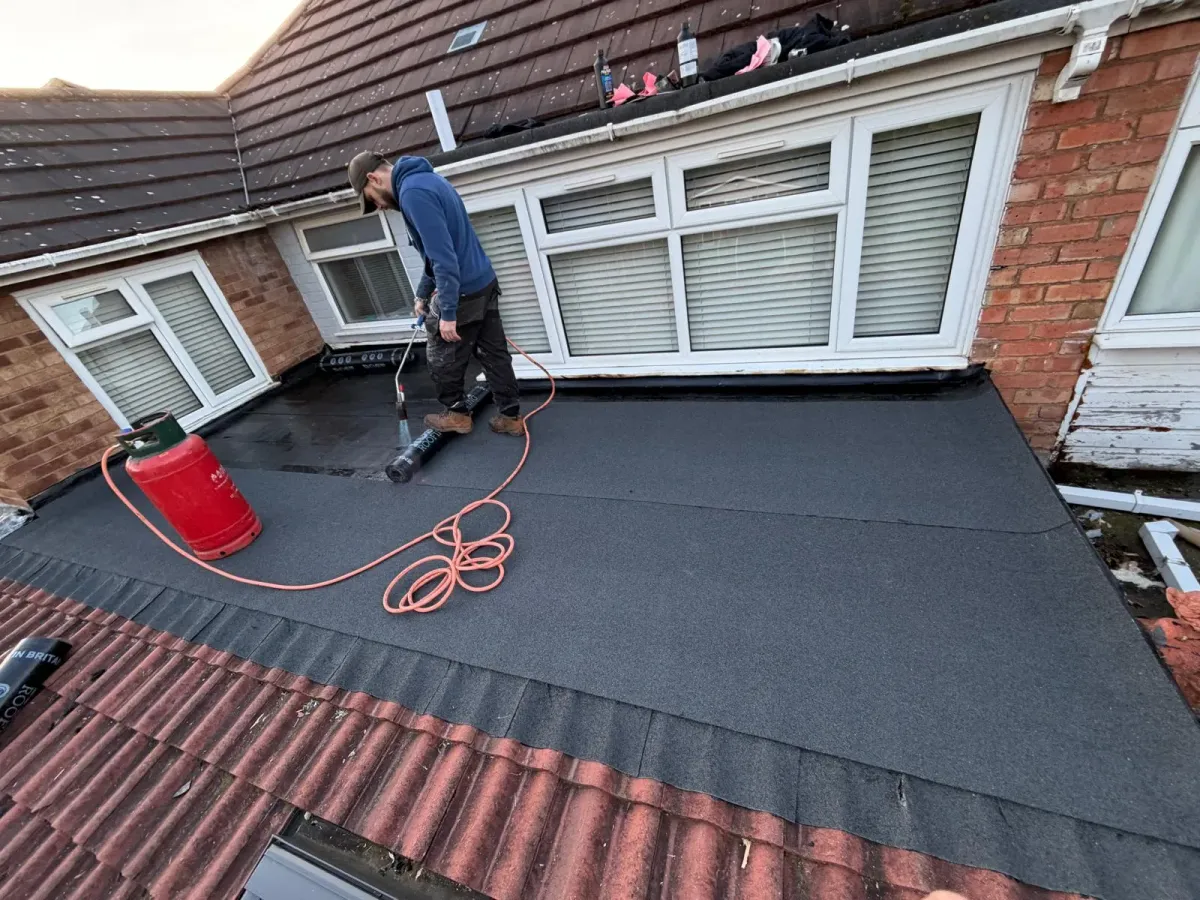 Roofer heat-welding mineral felt roofing membrane with a blowtorch on a Worcester residential flat roof