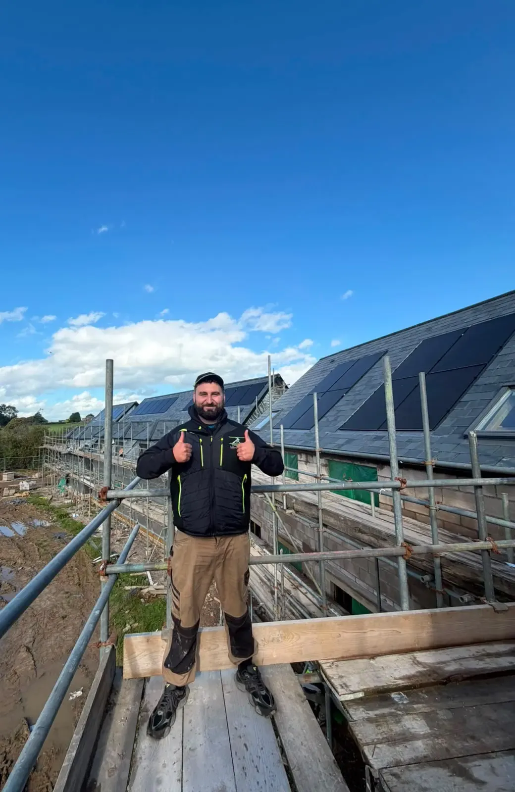 Roofer on scaffolding in front of a newly installed pitched slate roof