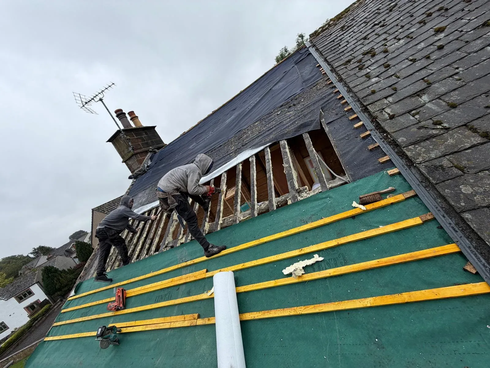 Roofers installing breathable membrane and timber battens during a pitched roof refurbishment