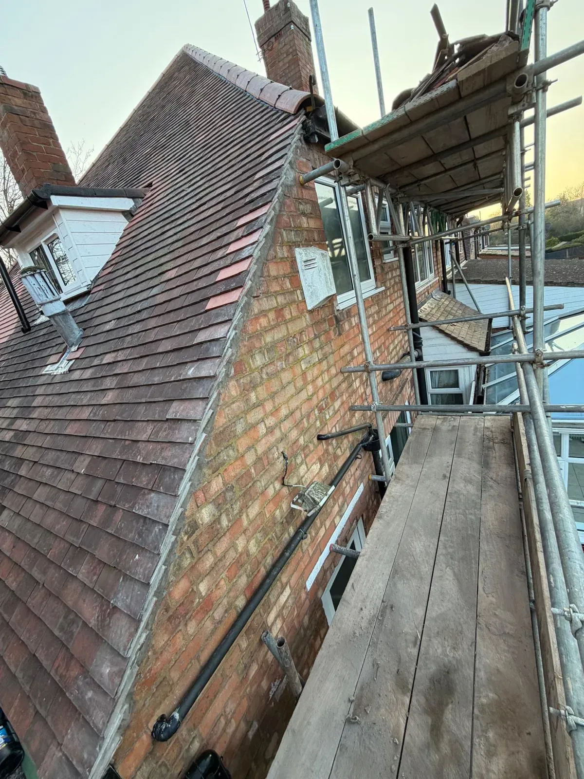 Scaffolding erected for pitched roof repairs and tile maintenance on a brick house in Worcester