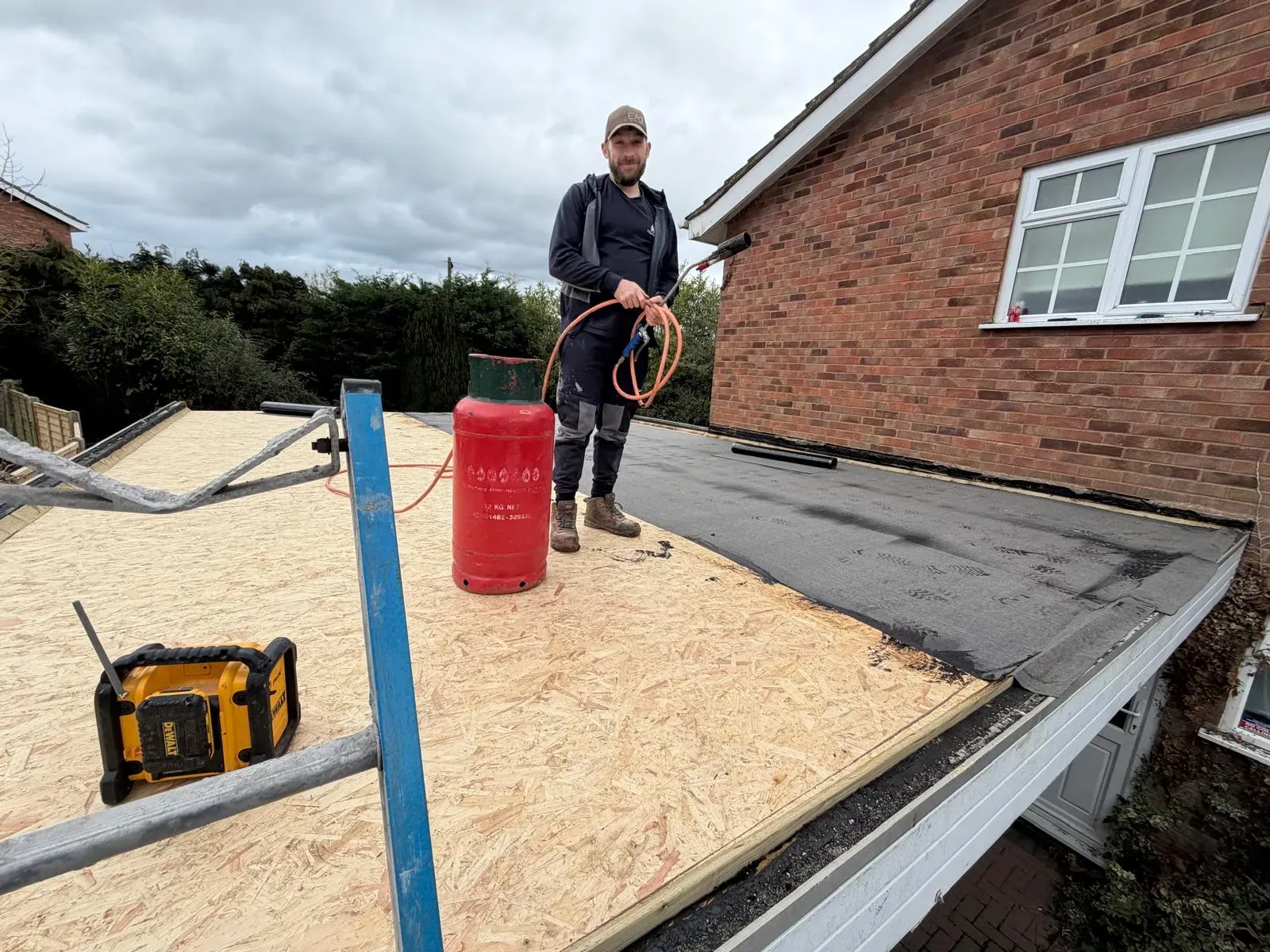 STORMPROOF roofer installing torch-on mineral felt flat roofing over fresh timber decking on a Worcester home extension