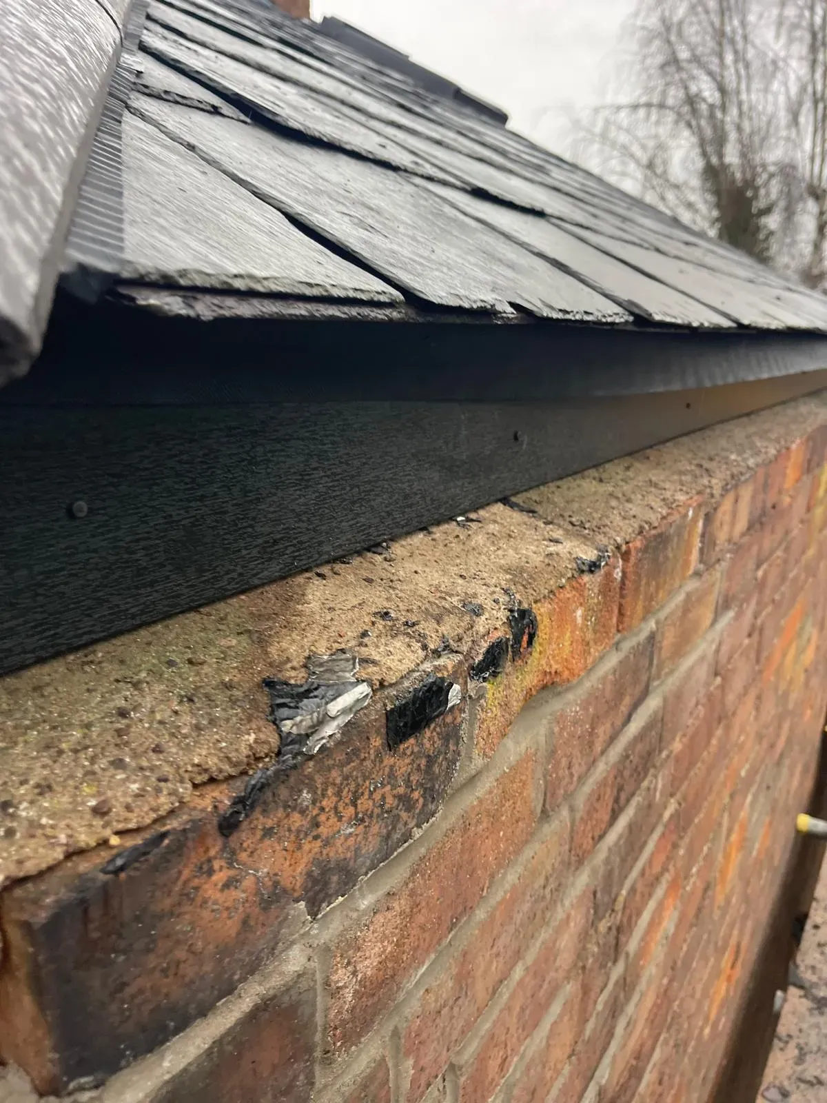 Natural slate roof verge detailing and trim installed above a brick exterior wall