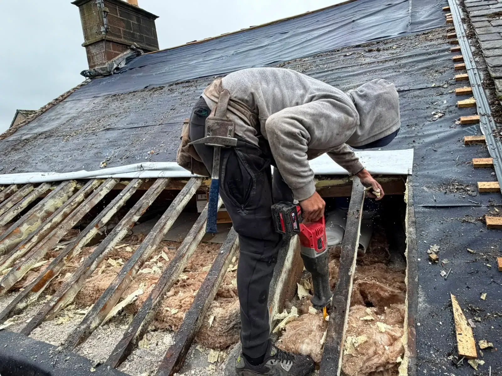 Roofer carrying out timber rafter repairs on a stripped pitched roof in Worcester
