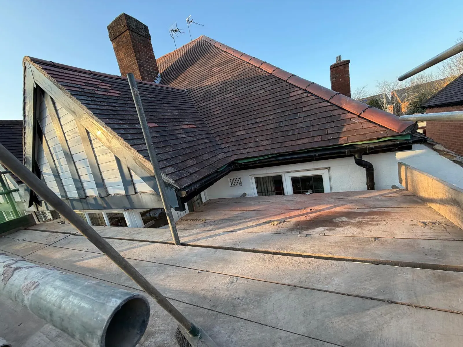Pitched clay tile roof and chimney stack undergoing repair works from scaffolding in Worcester
