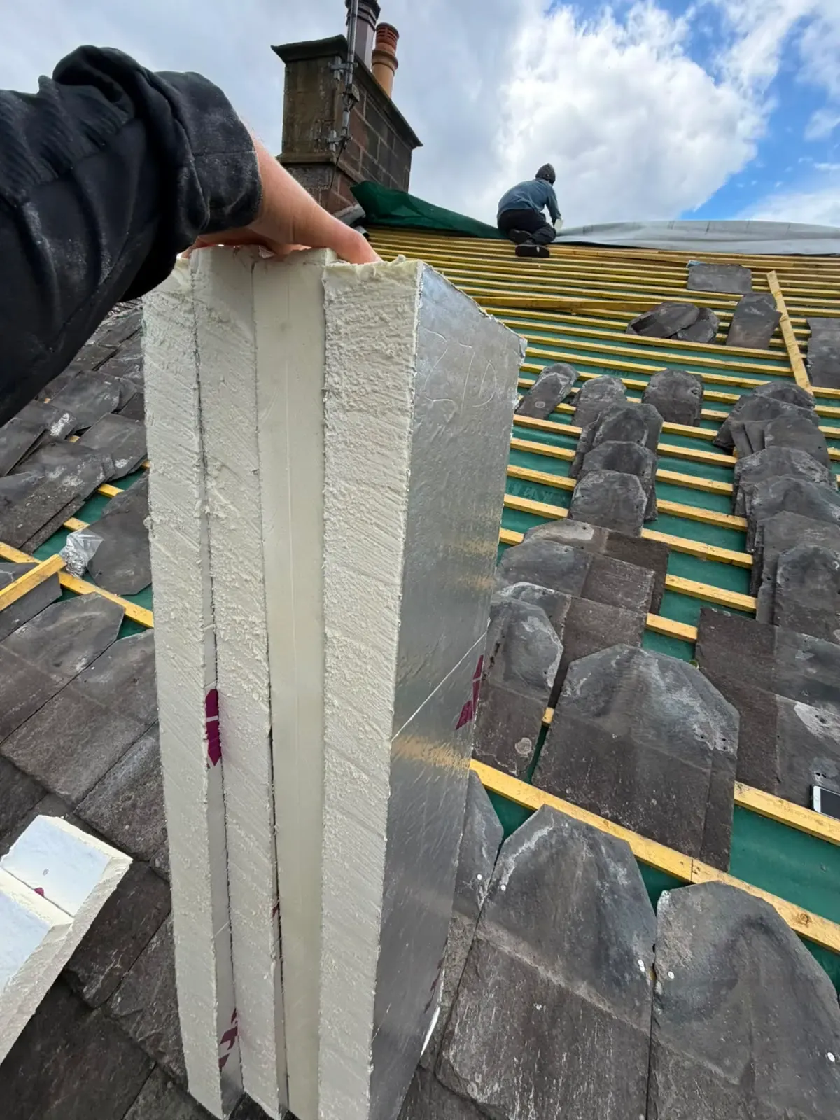 Pitched roof installation showing thick rigid board insulation, timber battens, and natural slates