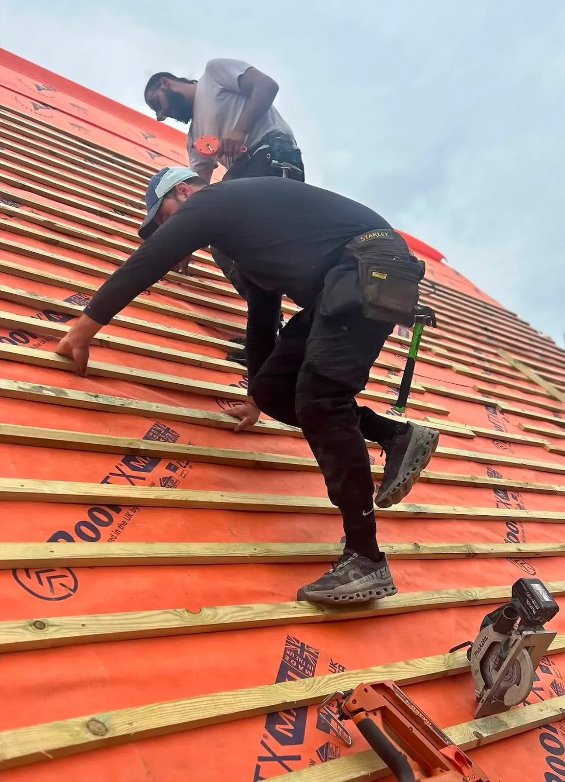 Roofers fixing timber battens over breathable roofing underlay during a pitched roof installation in Worcester