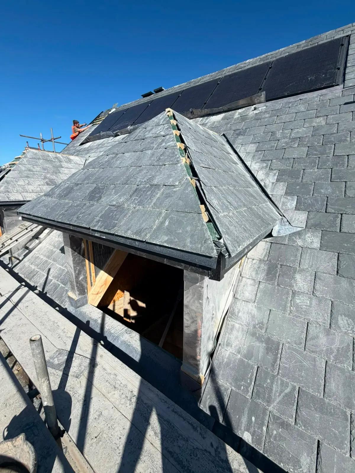 Natural slate pitched roof and dormer installation in progress with detailed lead flashing