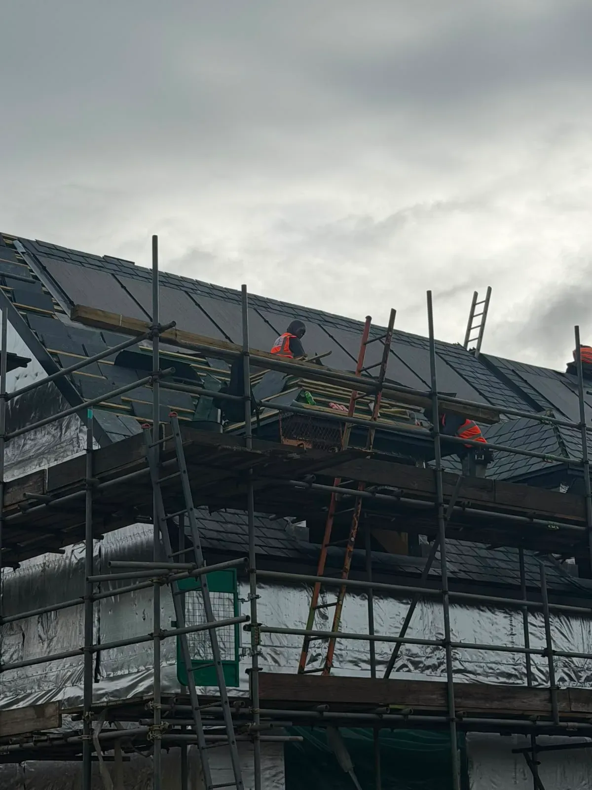 Roofers installing slate tiles on scaffolding during a pitched roof installation in Worcester