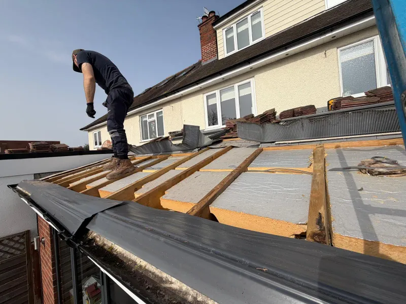 Roofer installing insulation boards between rafters on an extension warm roof replacement project